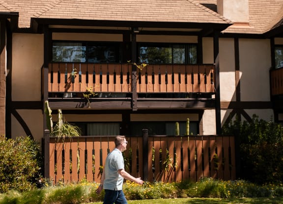 a man walks past a house with a wooden fence at Oak Park Apartments, California