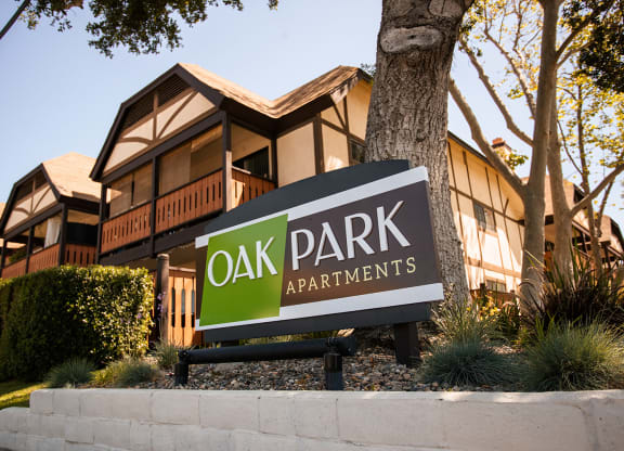 a sign for oak park apartments in front of a tree at Oak Park Apartments, California