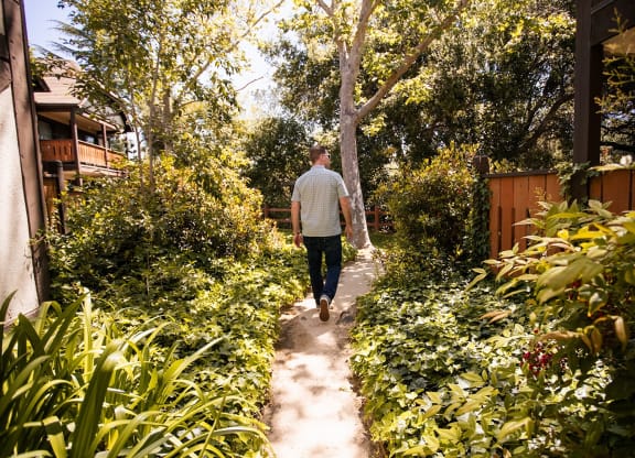 a man walks down a dirt path through a garden at Oak Park Apartments, Solvang, California