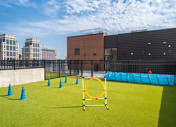 A playground with a blue and green surface, orange cones, and a yellow hoop at Sora Apartments, Minneapolis 55415