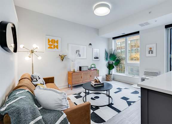 A modern living room with a couch, coffee table, and a large window. at Sora Apartments, Minneapolis 55415