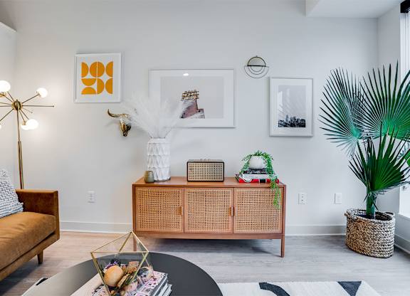 A living room with a brown sofa, a white coffee table, and a green plant. at Sora Apartments, Minneapolis