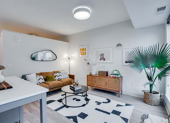 A living room with a white couch, a coffee table, and a plant. at Sora Apartments, Minneapolis 55415