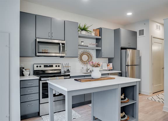 A modern kitchen with a white island and grey cabinets. at Sora Apartments, Minnesota, 55415
