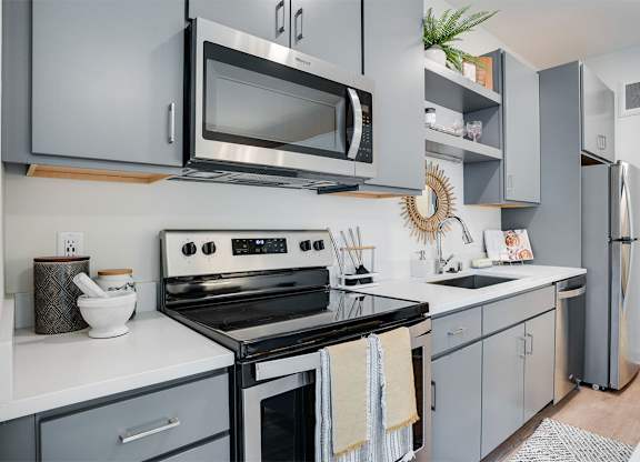 A modern kitchen with a stove, microwave, and refrigerator. at Sora Apartments, Minneapolis, MN, 55415