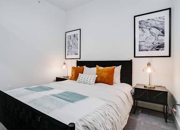 A bedroom with a large bed and two lamps at Sora Apartments, Minneapolis