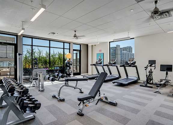 A gym with treadmills, dumbbells, and exercise equipment at Sora Apartments, Minnesota