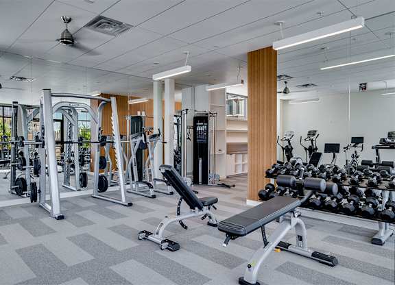 A spacious gym with a variety of equipment including treadmills, weights, and benches at Sora Apartments, Minneapolis