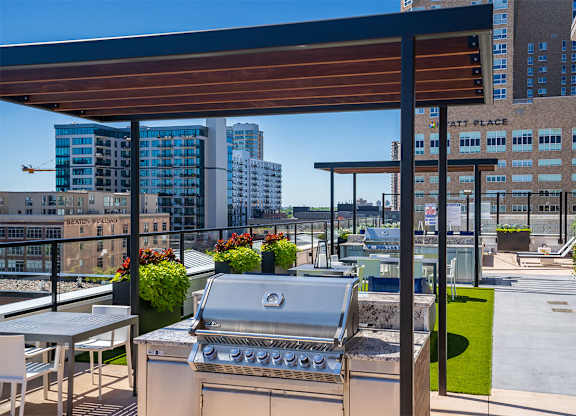 A barbecue grill on a patio with a table and chairs at Sora Apartments, Minnesota
