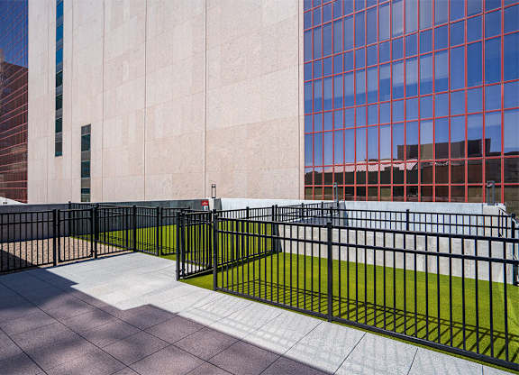 A black metal fence with a green lawn in front of a building. at Sora Apartments, Minneapolis, MN