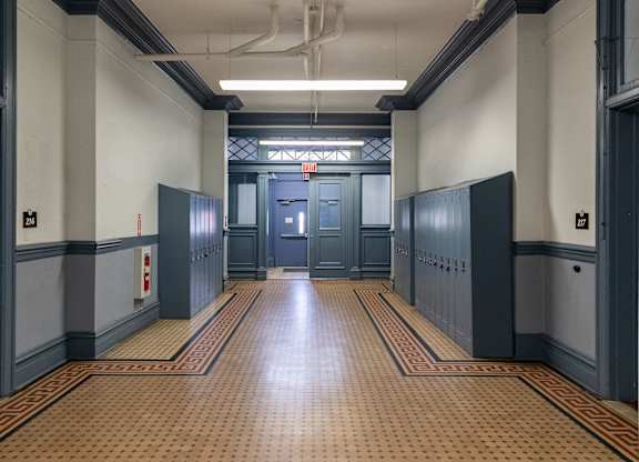 a hallway in a building with blue doors and a tiled floor