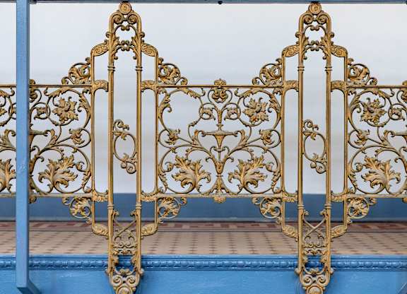 an ornate metal bed frame with gold filigree and blue