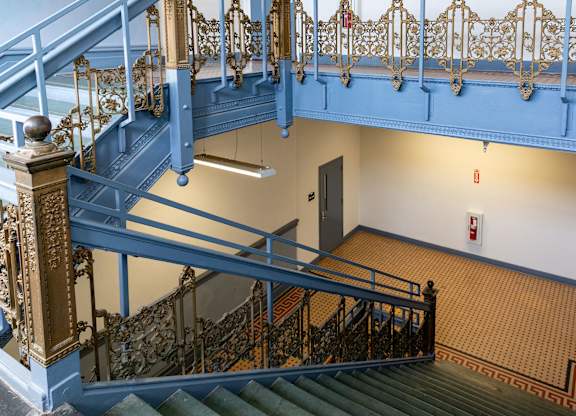 a view of the stairs in a building with blue railing and a door