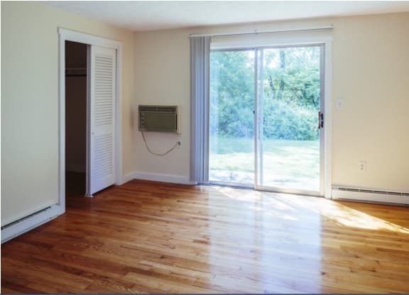 an empty living room with a sliding glass door and wood floors