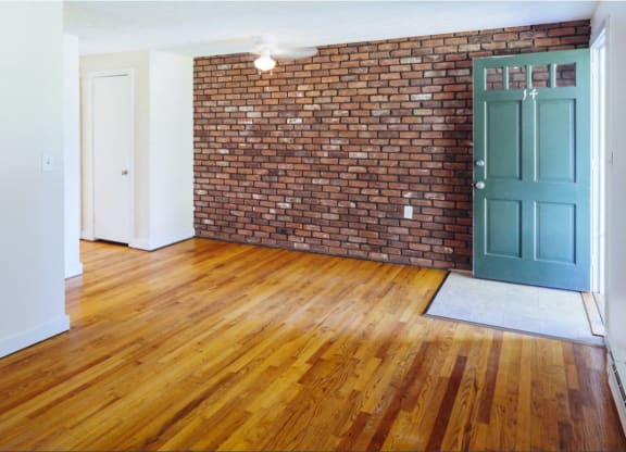 an empty living room with a brick wall and a blue door