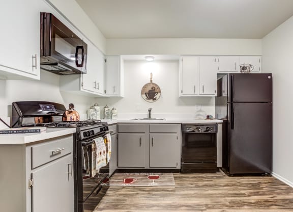 a kitchen with white cabinets and black appliances at The Township at St. Charles, St. Charles, IL