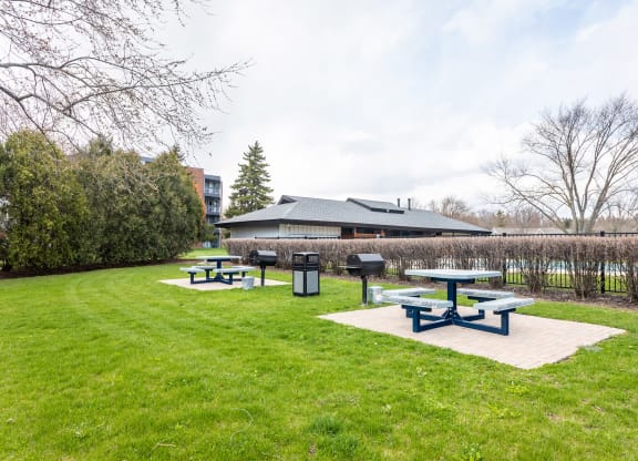 a group of picnic tables in a grassy area with a building in the background at The Township at St. Charles, St. Charles, IL
