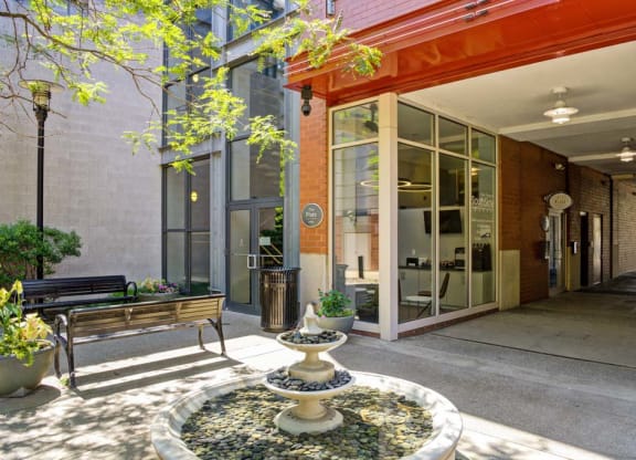 a courtyard with a fountain and a bench in front of a building at Flats at Southside, Pittsburgh, PA