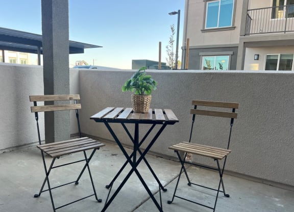 a table with two chairs and a plant on a balcony