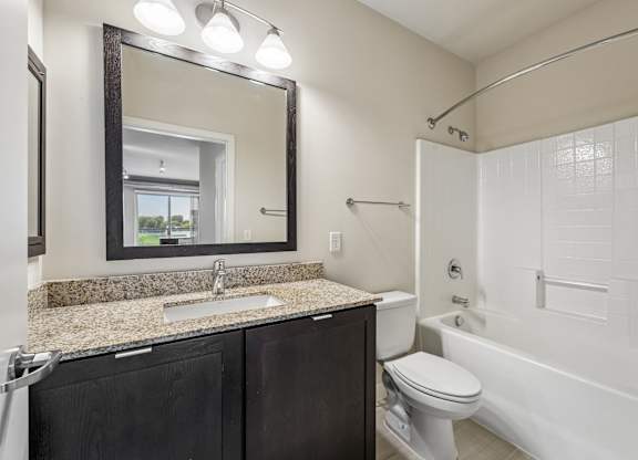 A bathroom with a sink, mirror, toilet and bathtub.