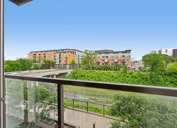 A balcony overlooks a green park and buildings.