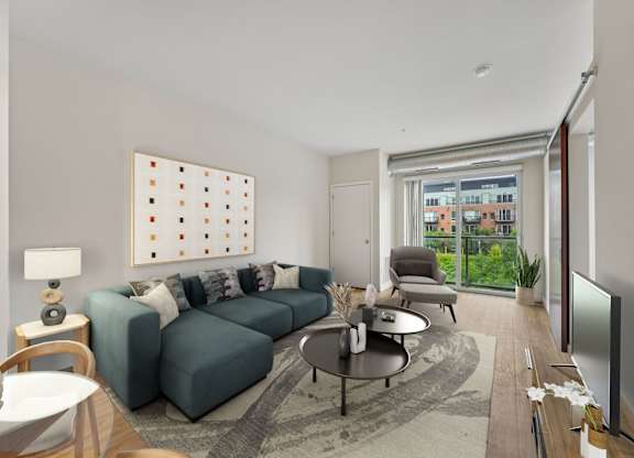 A living room with a grey sofa, a coffee table, a lamp, a painting, and a sliding glass door.