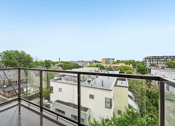 A balcony overlooks a residential area with houses and trees.