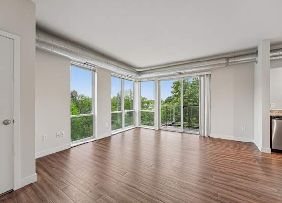 A room with wooden floors and a large window with a view of trees.