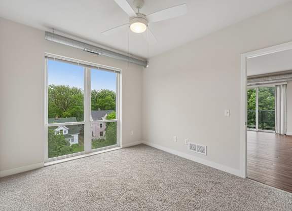 A room with a ceiling fan and sliding glass doors.