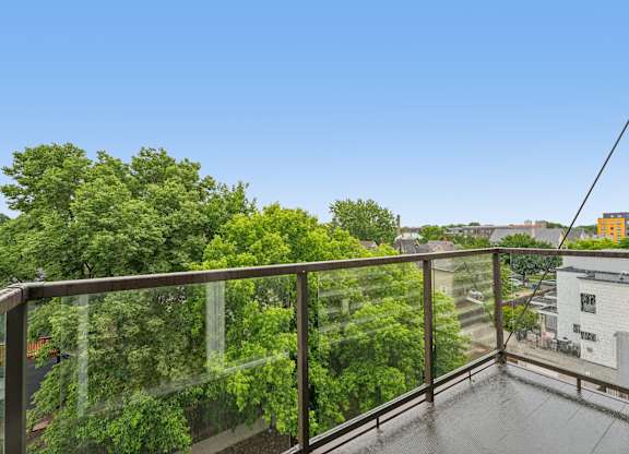 A balcony with a metal railing overlooks a lush green forest.
