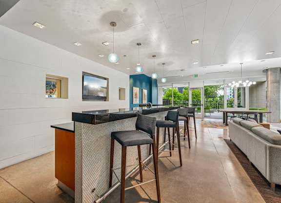 A modern bar area with a white counter and black stools.