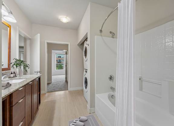 A bathroom with a white tub and a washing machine in the background.