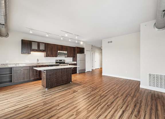A kitchen with wooden floors and a white wall.