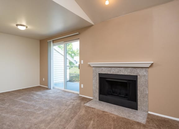 a living room with a fireplace and a door to a balcony at Murrayhill Park, Beaverton Oregon