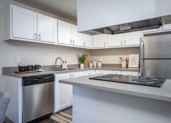 a kitchen with white cabinets and stainless steel appliances and a counter top at Sundial Apartments, Oregon