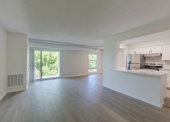 A spacious kitchen with white cabinets and a stainless steel refrigerator.