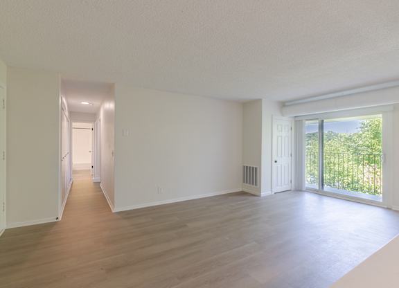 A long, empty hallway with white walls and wood flooring.