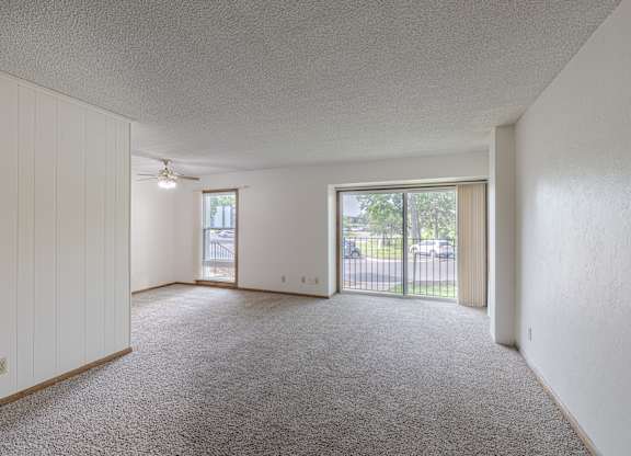 A spacious room with a carpeted floor and sliding glass doors.