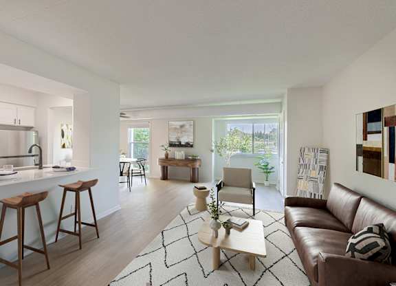 A modern living room with a brown leather couch and a white kitchen area.