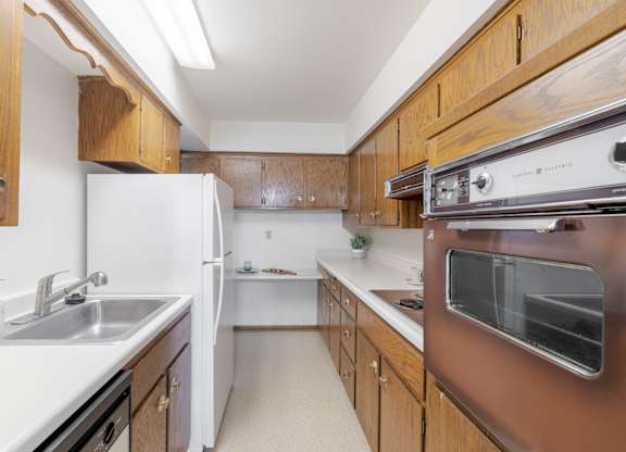 A kitchen with brown cabinets and white appliances.