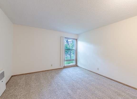 A room with a carpeted floor and a sliding glass door leading to a backyard.