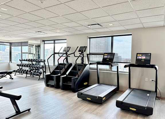 A gym with treadmills, elliptical machines, and weights.