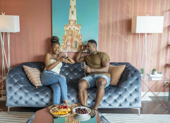 a couple sitting on a couch drinking wine  at West77 Apartments, Illinois, 60654