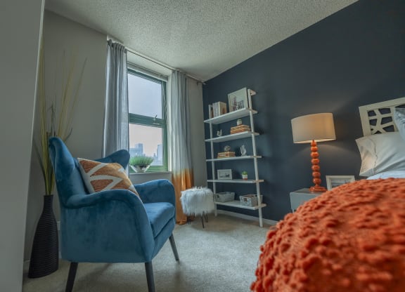 a bedroom with a blue chair and orange bedspread at West77, Chicago, IL