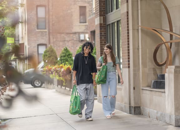 a man and a woman walking down the street with green bags  at West77 Apartments, Chicago, IL