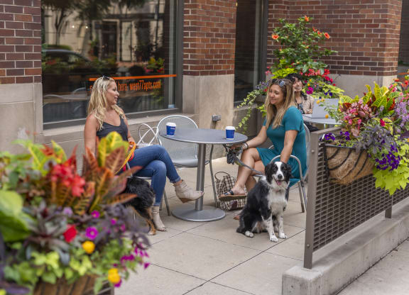 a couple of women sitting at a table with a dog  at West77 Apartments, Illinois, 60654