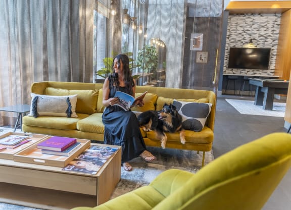 a woman sitting on a couch reading a book  at West77 Apartments, Illinois, 60654