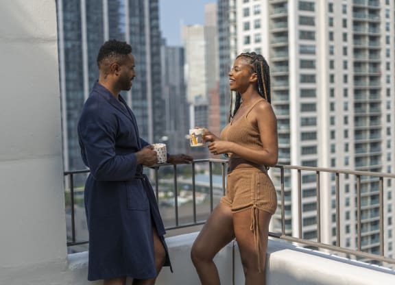 a man and woman standing on a balcony with a view of a large city at West77, Illinois, 60654
