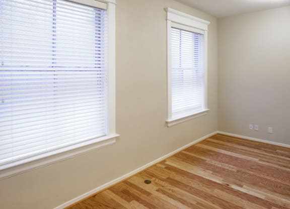 a room with a hard wood floor and two windows
