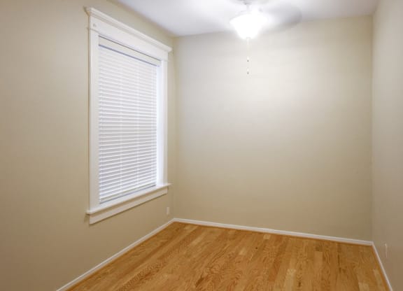a bedroom with a large window and a wooden floor